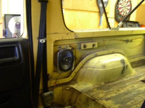 1982 Ford Bronco - The interior of a yellow vehicle shows a speaker installed on the side panel, with the cargo area visible in the background.