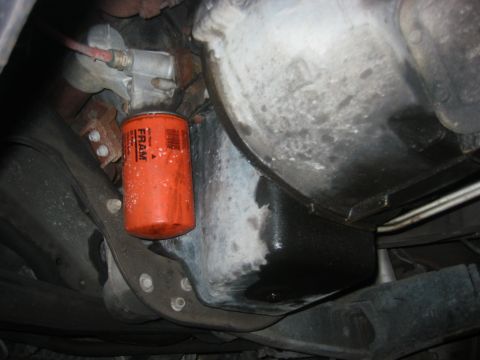 1989 Ford Bronco - Close-up view of an orange FRAM oil filter and a greasy oil pan, likely from underneath a vehicle.