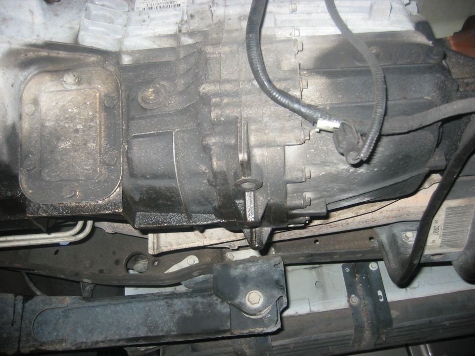 Underside view of vehicle transmission housing and frame parts. Supermotors.net logo visible