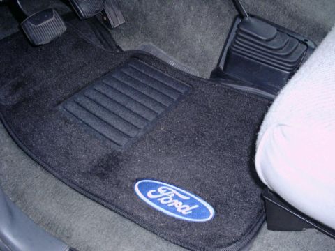 1992 Ford Bronco - Close-up of the driver's side floor area showing the pedals and a Ford-branded floor mat.