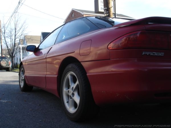 Red 1996 Ford Probe coupe, rear quarter view, parked on street, with another SUV in background