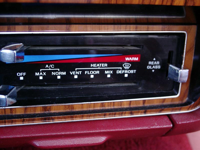 Woodgrain HVAC slider control panel with rear glass switch in a red dashboard