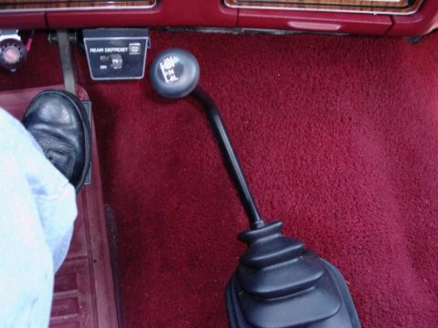 1984 Ford Bronco - The interior of a vehicle displays a four-wheel-drive shifter and a rear defrost control panel.