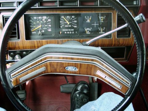 1984 Ford Bronco - The dashboard features wood grain accents and a Ford emblem on the steering wheel, with various gauges visible.