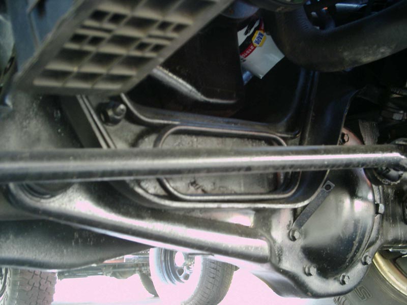 Clean black-painted front differential housing, axle beam and tie rod seen from underneath a truck