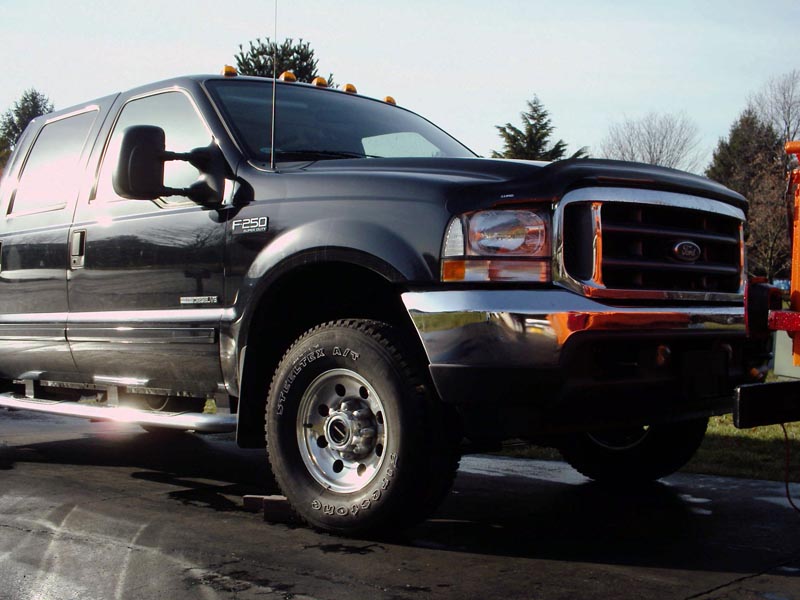 Black Ford F-250 Super Duty Power Stroke crew cab, front three-quarter, hitched to equipment
