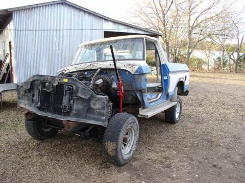 1978 Ford Bronco - A partially disassembled Ford truck sits outdoors next to a metal building.