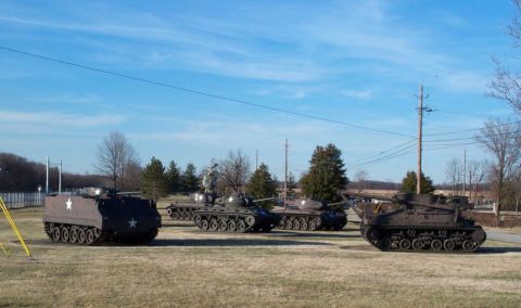 1998 Ford Crown Victoria - A collection of military vehicles, including tanks, are displayed outdoors on a sunny day.