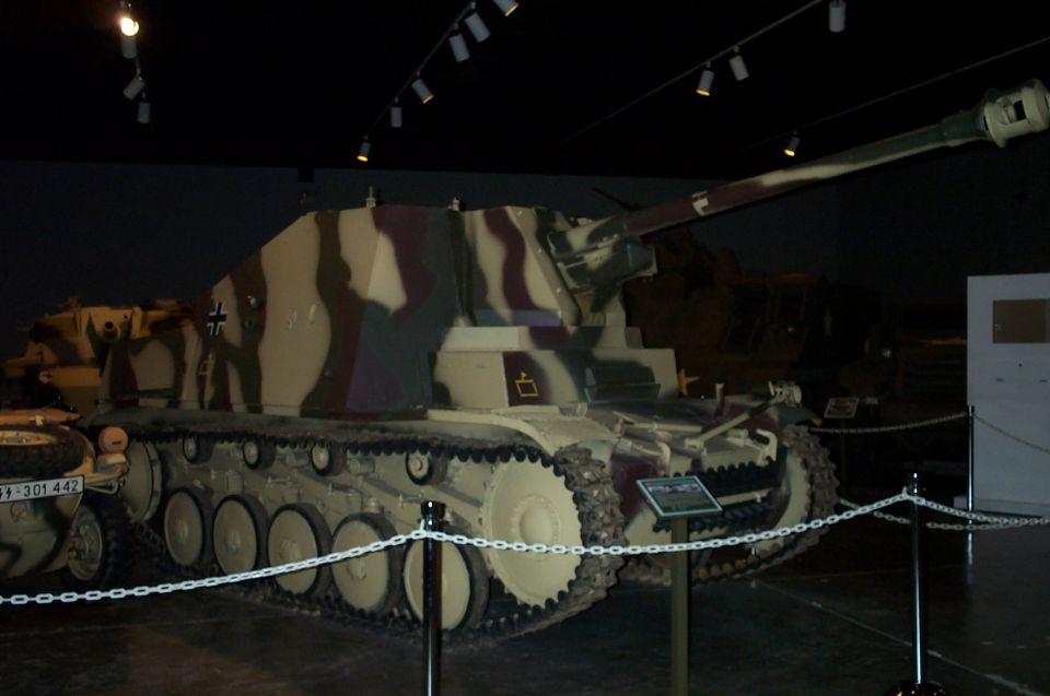 Camouflaged WWII German self-propelled gun on tracked chassis displayed in a museum