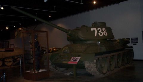 1998 Ford Crown Victoria - A Soviet T-34 tank is on display in a museum, with a mannequin in a glass case nearby.