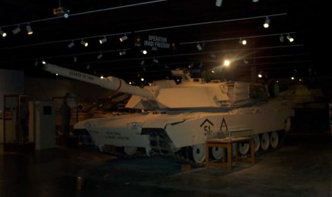1998 Ford Crown Victoria - A military tank is displayed indoors under spotlights, with a sign indicating "Operation Iraqi Freedom" overhead.