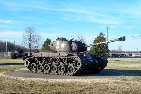 1998 Ford Crown Victoria - A military tank is displayed outdoors with a second tank visible in the distance under a clear sky.