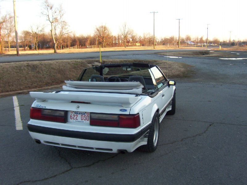 White convertible with a rear spoiler and Arkansas license plate 622 DSO parked on asphalt