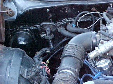 1973 Ford Ranchero - Engine bay view showing a large black flexible air intake duct running to the air cleaner, with black rubber vacuum hoses, wiring, and a bl…