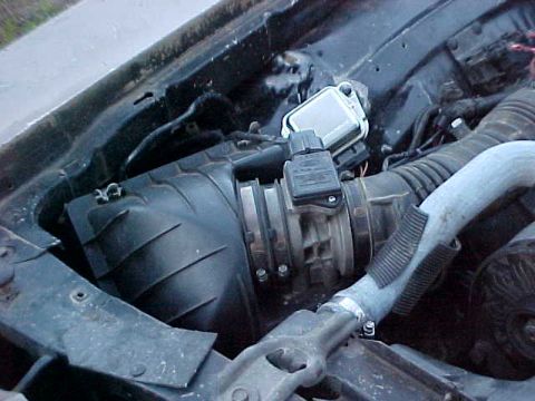 1973 Ford Ranchero - Close-up of an engine bay showing a black plastic air filter housing connected to a mass air flow sensor with a metallic/chrome top and a b…