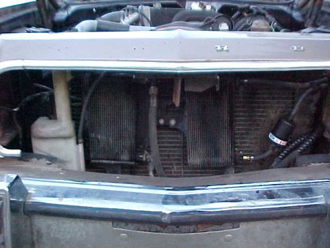 1973 Ford Ranchero - Front-end view of a vehicle with the grille and front bumper removed, exposing the radiator, radiator support, coolant overflow bottle, and…
