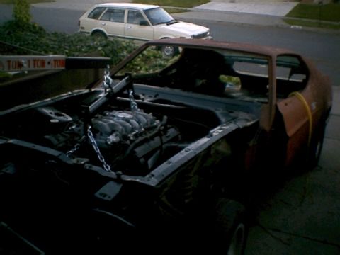 2000 Mercury Grand Marquis - Engine removal in progress on a rusty vehicle, with a white station wagon visible in the background.