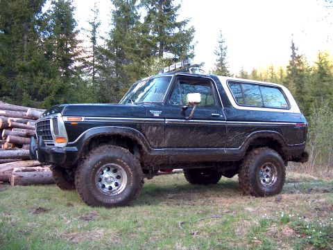 1979 Ford Bronco - Mud-splattered 1978 Ford Bronco with off-road lights on the roof, parked outdoors.