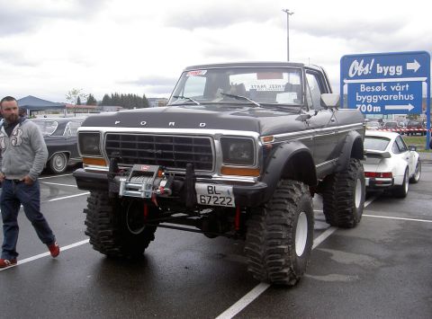 1979 Ford Bronco - This modified 1979 Ford Bronco features a front winch and massive off-road tires, parked next to a white sports car.