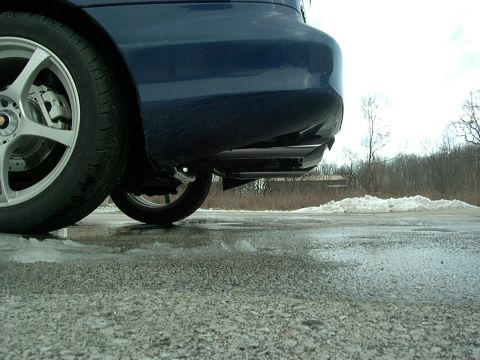 1995 Ford Probe - Close-up of the rear wheel and bumper of a vehicle on a wet, partially frozen road.
