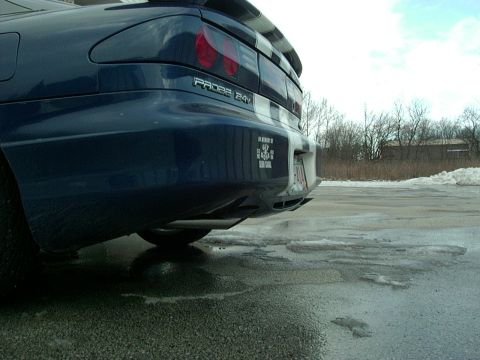 1995 Ford Probe - Rear view of a blue 1995 Ford Probe with a sticker on the bumper, parked in a wet lot with snow in the background.