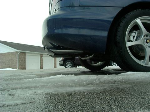 1995 Ford Probe - Low angle shot of a blue car's rear bumper and wheel, with another vehicle visible in the background.