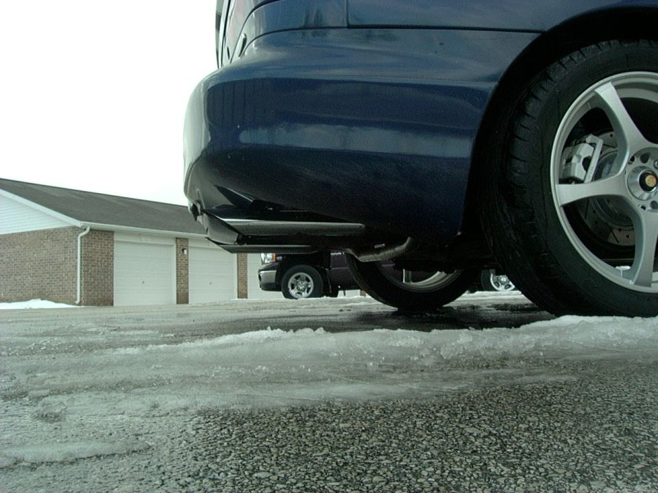 Blue car rear bumper and wheel with exhaust pipe visible