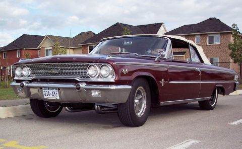 1963 Ford Galaxie - A maroon 1963 Ford Galaxie convertible is parked curbside in front of suburban houses.