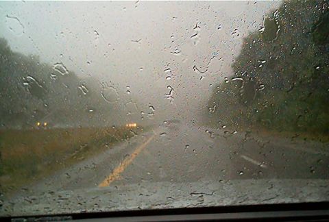 1985 Ford LTD Crown Victoria - Driving on a wet road during a downpour, visibility is significantly reduced by rain on the windshield.