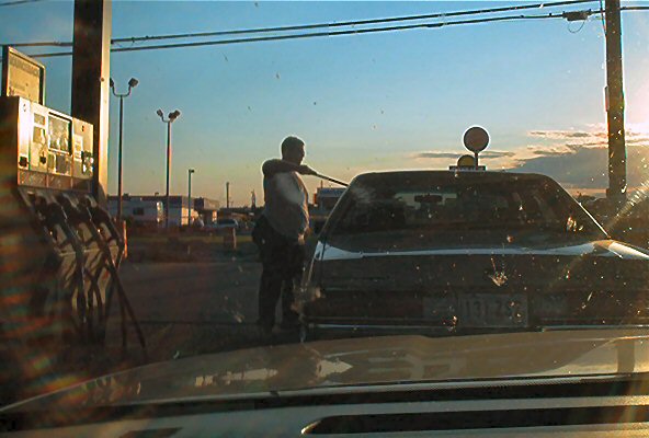 Dark sedan with a license plate reading N13175, being cleaned by a person at a gas station