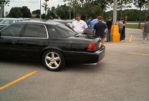 1985 Ford LTD Crown Victoria - A black sedan is parked in a lot, viewed from the rear quarter.