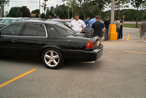 Black sedan with aftermarket wheels parked in a lot, rear quarter view