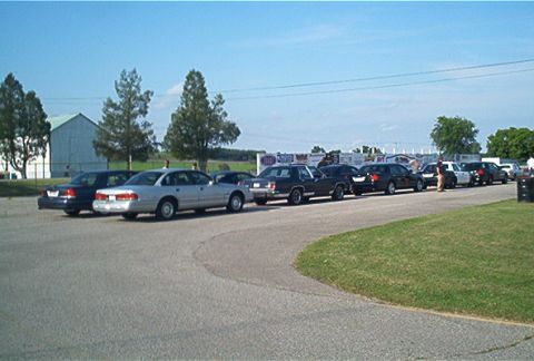 1985 Ford LTD Crown Victoria - Several sedans, including a silver 1985 Ford Crown Victoria LTD, are parked in a line on a sunny day.