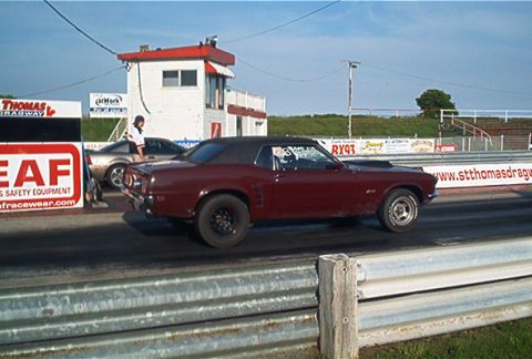 1985 Ford LTD Crown Victoria - A maroon coupe with a black top is seen on a drag strip, with another vehicle behind it.