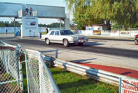 1985 Ford LTD Crown Victoria - White 1985 Ford Crown Victoria LTD on a drag strip, with a starting tower in the background.