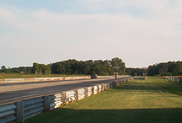 Car on a drag strip with trees and sky in background
