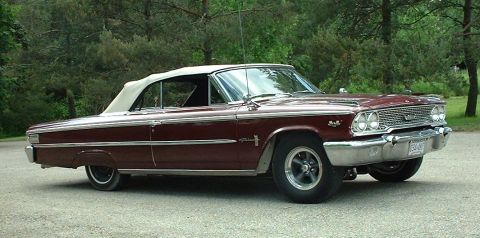 1963 Ford Galaxie - This maroon 1963 Ford Galaxie convertible is shown from a front three-quarter perspective against a backdrop of trees.