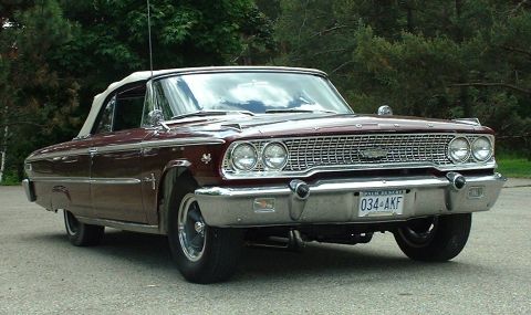 1963 Ford Galaxie - A maroon 1963 Ford Galaxie convertible is shown from a three-quarter front view, highlighting its distinctive grille and chrome details.