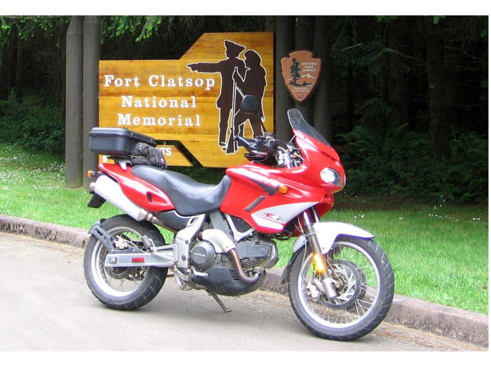 Red and white adventure motorcycle parked at Fort Clatsop National Memorial sign