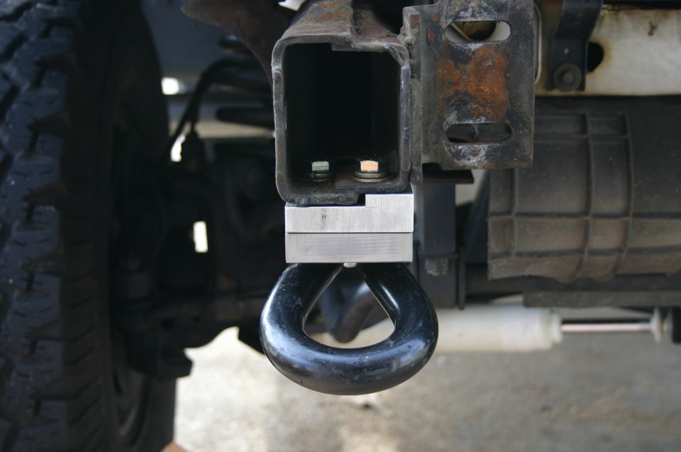 Close-up of a black tow hook mounted to a vehicle's frame, with a tire visible on the left