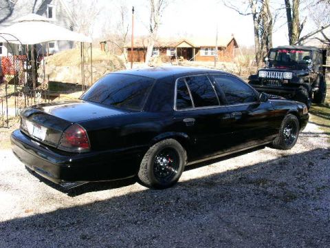 2001 Ford Crown Victoria - A black 2001 Ford Crown Victoria sedan is parked outdoors next to a black Jeep.