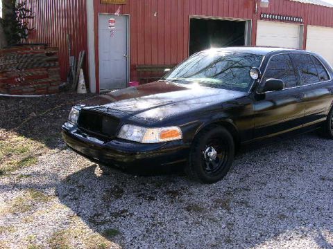 2001 Ford Crown Victoria - A black 2001 Ford Crown Victoria is parked in front of a red building.