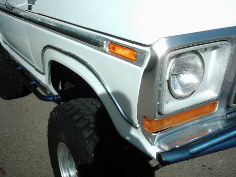 1978 Ford Bronco - Close-up of the front fender and wheel well of a white 1978 Ford Bronco with off-road tires.