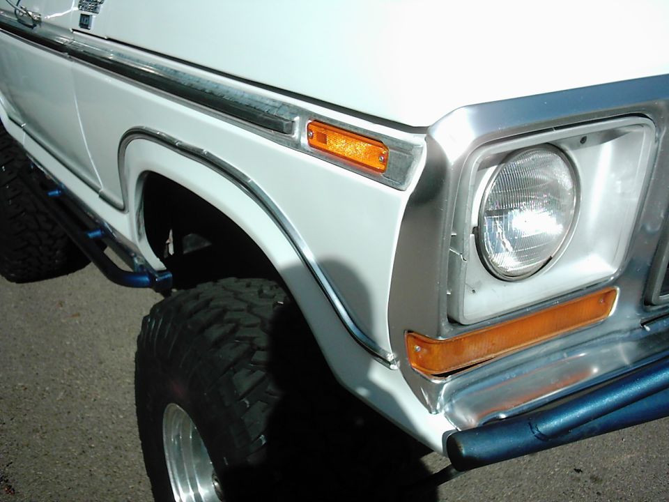 1978 Ford Bronco front fender with chrome trim, orange marker light, and large off-road tire