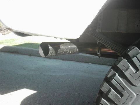 1978 Ford Bronco - The rear section of a vehicle shows dual exhaust pipes and a portion of a large tire.