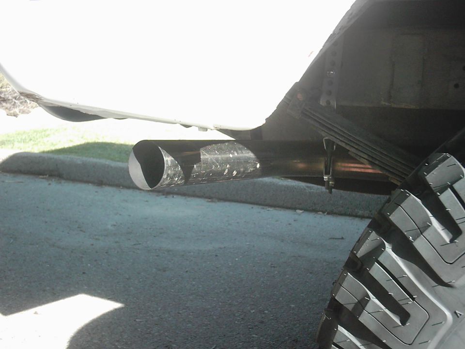 Close-up of dual exhaust pipes and a large tire on a vehicle