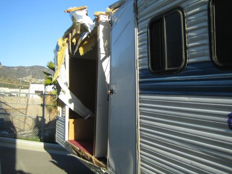 1968 Ford Mustang - A trailer has sustained significant damage to its roof and side, revealing its internal structure.