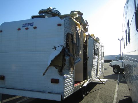 1968 Ford Mustang - A trailer has sustained significant damage, revealing its internal insulation and structure, parked in a lot with other vehicles.