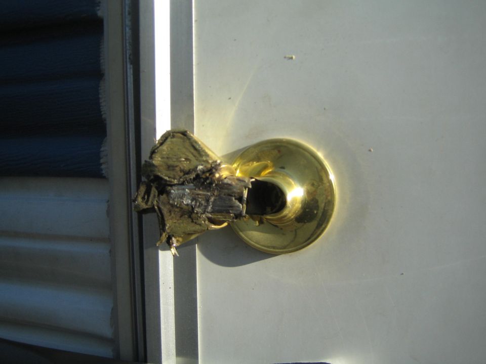 Door handle is broken and charred, with wood splintering out