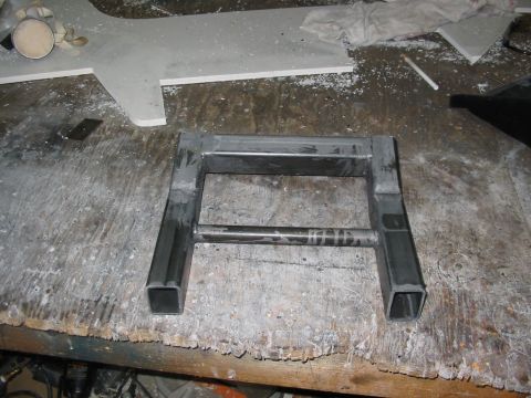 1985 Ford Crown Victoria LTD - A metal frame part sits on a workbench covered in debris and tools.